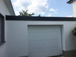 Weißes Garagentor mit grauem Rahmen an einer Wand in einem Wohnbereich.