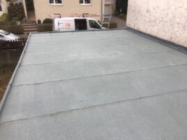 Flachdach mit grauer Oberfläche und mehreren Fugen auf einem Garagengebäude.