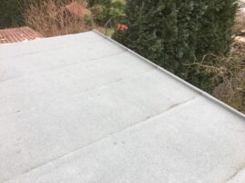 Flachdach mit grauer Abdichtung und leicht strukturiertem Material auf einer Garage.