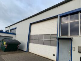 Fassade eines Industriegebäudes mit einem großen Rolltor und einer Eingangstür.