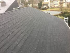 Dach mit schwarzen Schindeln, das eine schräge Fläche abdeckt und eine strukturierte Oberfläche zeigt.