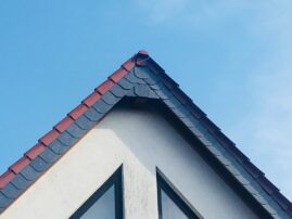 Dachgipfel mit roten und grauen Schindeln unter einem blauen Himmel.