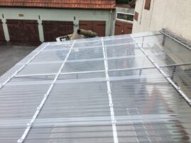Transparente Wellenplattendachkonstruktion auf einem Gebäude mit Metallrahmen.