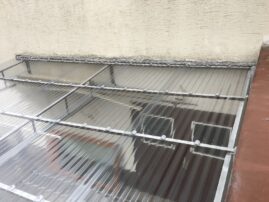 Wellenplattendach aus transparentem Material auf einem Gebäude mit Metallrahmen.